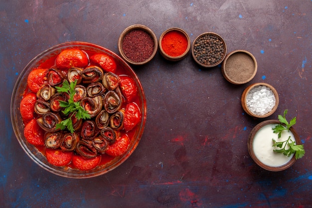 Photo gratuite vue de dessus repas de légumes cuits délicieux tomates et aubergines avec assaisonnements sur la surface sombre