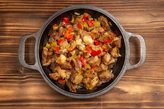 Vue de dessus repas de légumes cuits avec de la viande et des poivrons en tranches sur le bureau brun