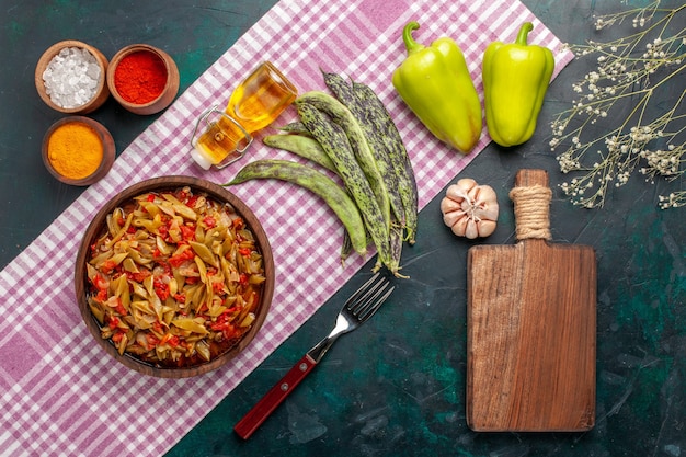 Vue de dessus repas de légumes en tranches avec assaisonnements sur fond bleu foncé