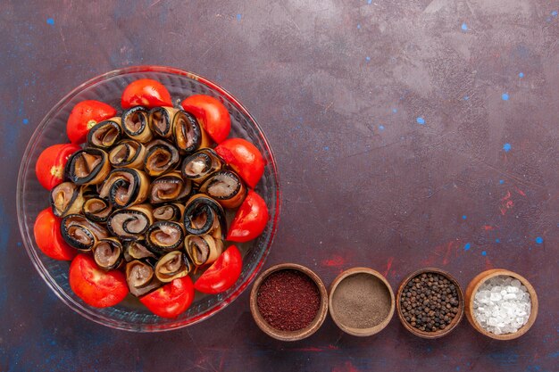 Vue de dessus repas de légumes en tranches et tomates roulées aux aubergines et assaisonnements sur le fond sombre