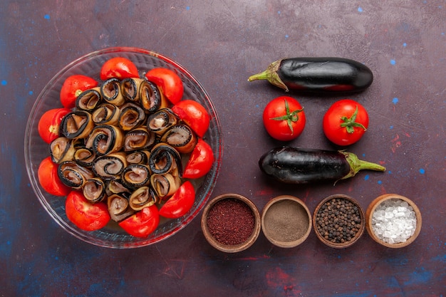 Vue de dessus repas de légumes en tranches et tomates roulées aux aubergines et assaisonnements sur sol sombre