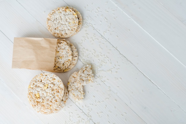 Une vue de dessus de riz soufflé avec des grains sur un bureau en bois blanc