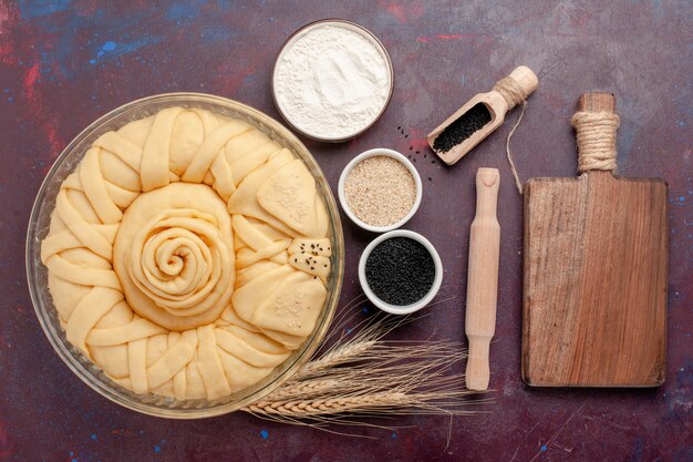 Vue de dessus rond de tarte cru formé avec des assaisonnements sur une surface sombre