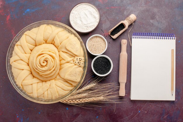 Vue de dessus rond de tarte cru formé avec bloc-notes sur une surface sombre