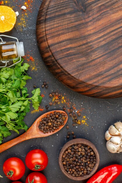 Vue de dessus ronde planche de bois poivre noir dans un petit bol tomates ail coriandre citron sur table