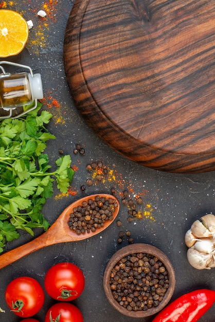 Vue de dessus ronde planche de bois poivre noir dans un petit bol tomates ail coriandre citron sur table