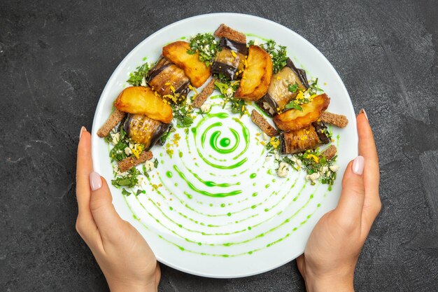 Vue de dessus des rouleaux d'aubergines cuites avec des pommes de terre à l'intérieur de la plaque sur le plat de fond sombre repas dîner pomme de terre