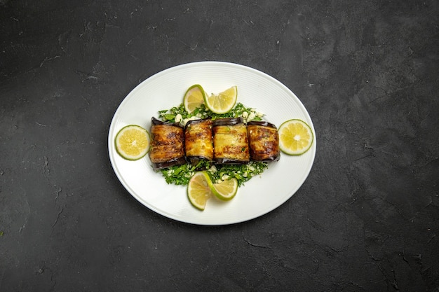 Photo gratuite vue de dessus des rouleaux d'aubergines salés avec des tranches de citron sur la surface sombre des fruits de la cuisson du repas du dîner