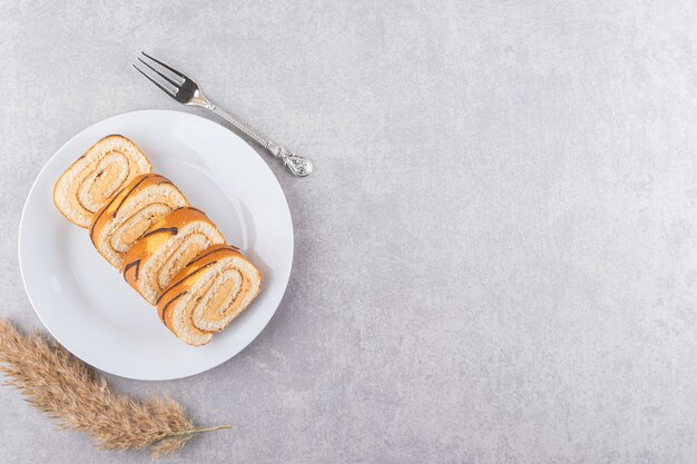 Vue de dessus des rouleaux de gâteaux faits maison sur plaque blanche