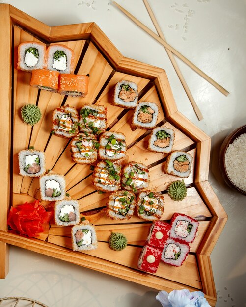 Vue de dessus des rouleaux de sushi mis en place sur un plateau à sushi en bois en forme d'éventail