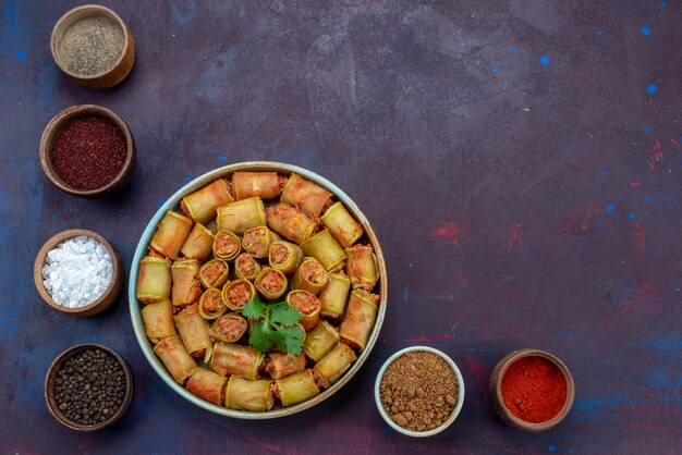 Vue de dessus des rouleaux de viande roulés à l'intérieur des courges avec des assaisonnements sur le bureau sombre repas de viande repas de légumes dîner