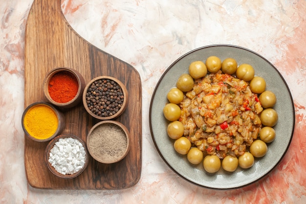 Photo gratuite vue de dessus de la salade d'aubergines rôties et prunes marinées sur des bols avec des épices sur une planche à découper sur une surface nue