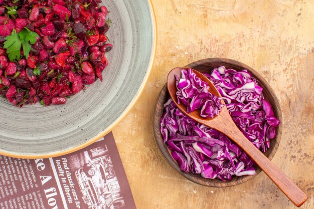 Vue de dessus salade de betteraves saine sur une assiette grise faite d'un bouquet de persil et d'un bol de chou rouge haché sur un fond en bois avec un petit espace pour le texte