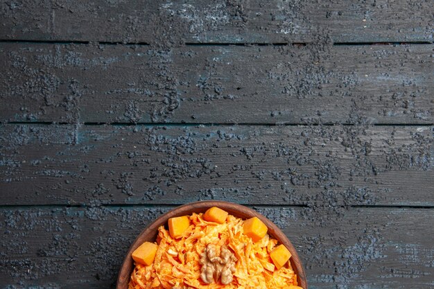 Vue de dessus salade de carottes fraîches salade râpée aux noix et à l'ail sur un bureau sombre régime couleur mûre salade santé