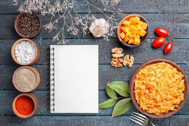 Photo gratuite vue de dessus salade de carottes râpées avec noix d'ail et assaisonnements sur le bureau sombre salade de régime santé couleur orange mûre