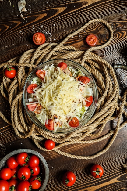 Vue de dessus salade césar aux tomates cerises dans un bol avec corde sur la table