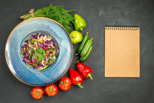 Vue de dessus de la salade de chou frais avec des verts et des légumes sur fond sombre