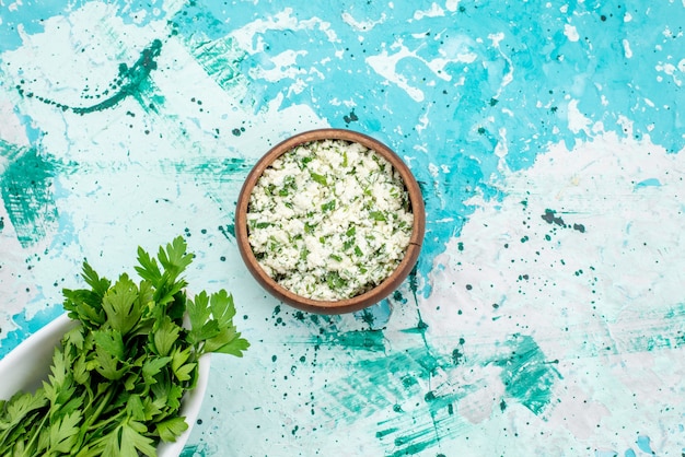 Vue de dessus de la salade de choux frais tranchés avec des verts à l'intérieur d'un bol brun sur bleu vif, salade de légumes verts fraîcheur snack