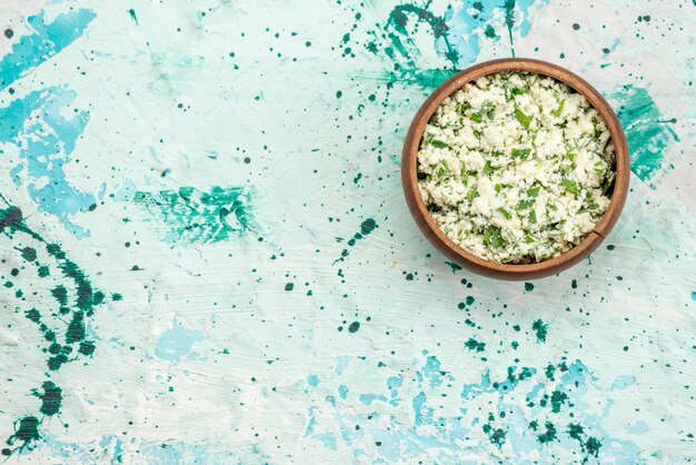 Vue de dessus de la salade de choux frais tranchés avec des verts à l'intérieur d'un bol brun sur un sol bleu vif alimentaire vert salade de légumes fraîcheur snack