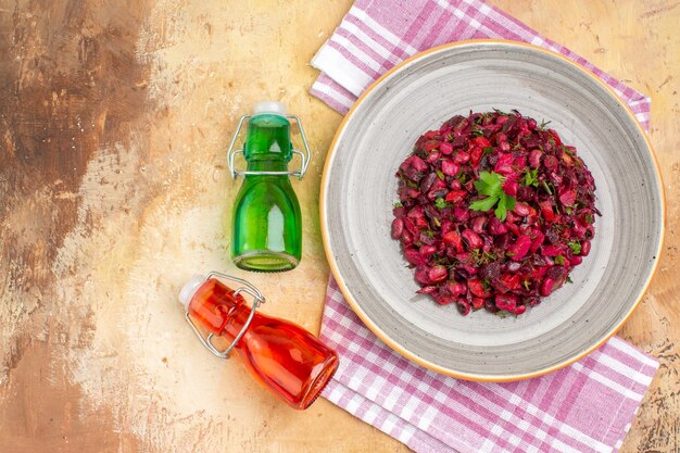 Vue de dessus Salade exquise sur une assiette en céramique avec des bouteilles d'huile accrocheuses et une serviette à carreaux violette