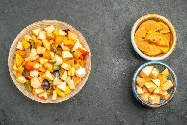 Vue de dessus de la salade fruitée avec des fruits en tranches sur fond gris