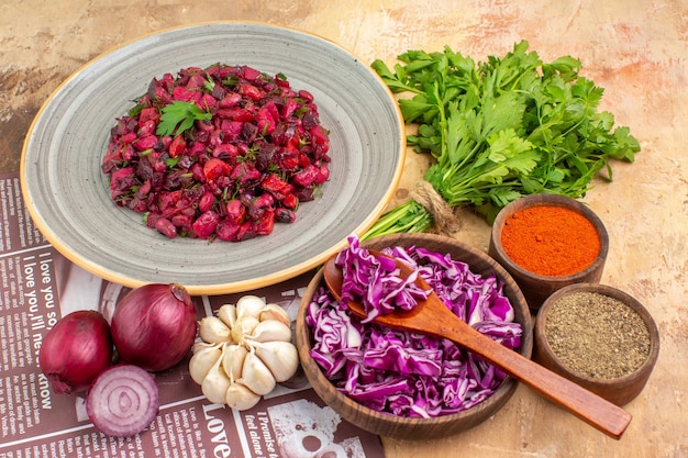 Photo gratuite vue de dessus salade de légumes sur une assiette en céramique faite d'oignons rouges ail bouquet de persil et poivre noir poivre moulu curcuma et chou rouge haché sur fond de bois