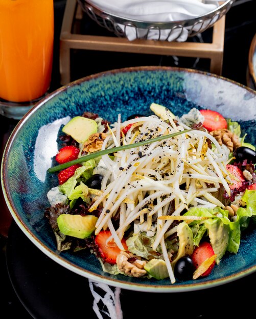 Vue de dessus salade de légumes aux fruits, fraises et raisins dans une assiette