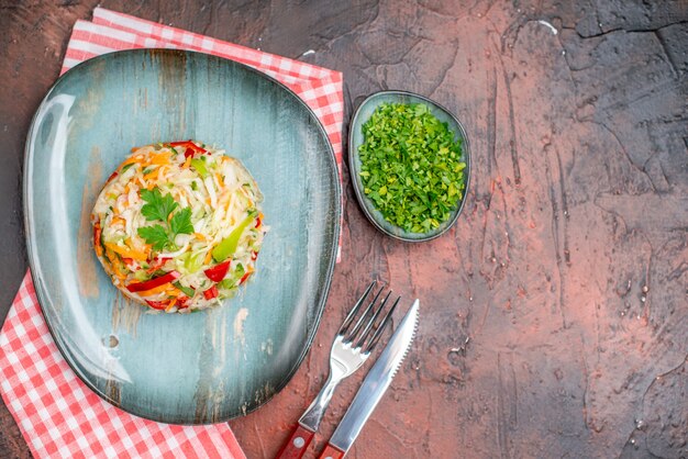 Vue de dessus de la salade de légumes en forme de plaque intérieure ronde sur la table sombre