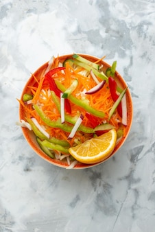 Vue de dessus salade de légumes frais à l'intérieur de la plaque sur une surface blanche aliments sains repas régime dîner horizontal