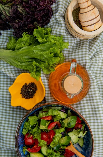 Vue de dessus de salade de légumes avec de la laitue basilic poivre noir concasseur d'ail beurre fondu sur la surface de tissu à carreaux