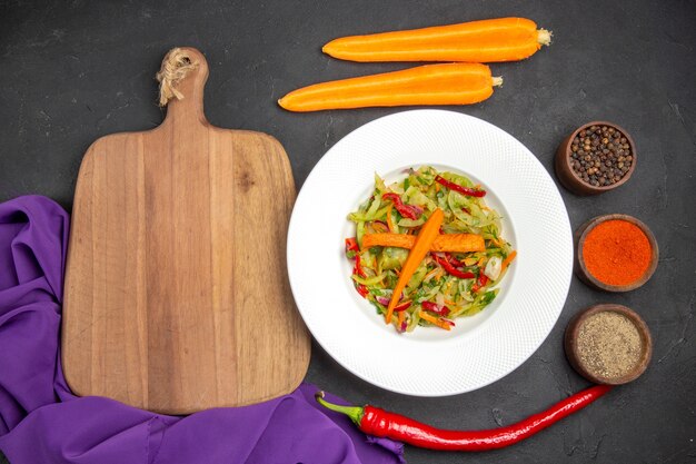 Vue de dessus salade de légumes la planche à découper épices carottes nappe violette