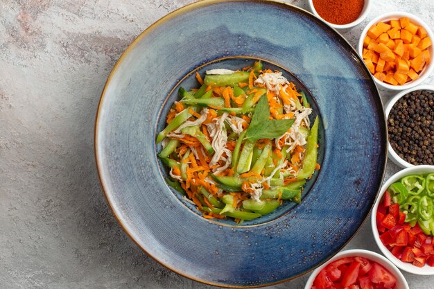 Vue de dessus salade de légumes en tranches avec assaisonnements sur fond blanc