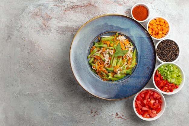 Vue de dessus salade de légumes en tranches avec assaisonnements sur fond blanc