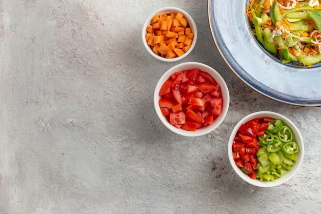 Vue de dessus salade de légumes en tranches à l'intérieur de la plaque sur un bureau blanc clair