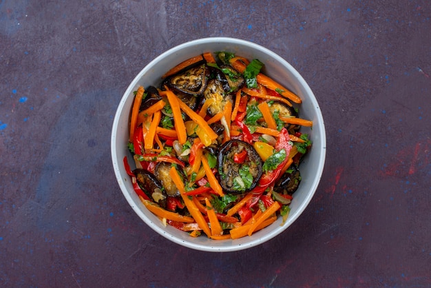 Vue de dessus salade de légumes en tranches à l'intérieur de la plaque sur la surface bleu foncé