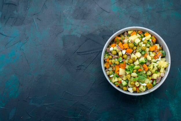 Vue de dessus salade de légumes en tranches poivrée de tranches de poulet à l'intérieur de la plaque sur le bureau bleu foncé