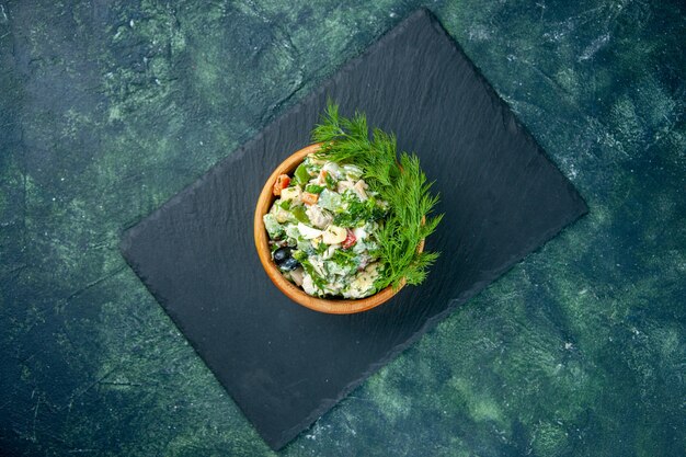 Vue de dessus salade de légumes avec des verts à l'intérieur de petit pot sur fond bleu foncé