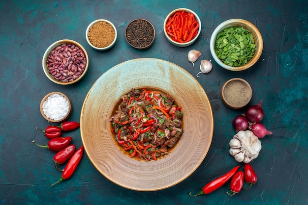 Vue de dessus salade de légumes à la viande en tranches à l'intérieur de la plaque avec des assaisonnements verts sur la table bleu foncé salade alimentaire ingrédient végétal