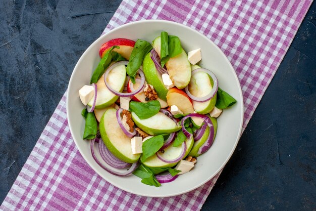 Vue de dessus salade de pommes fraîches sur plateau blanc nappe à carreaux blanc violet sur table bleu foncé