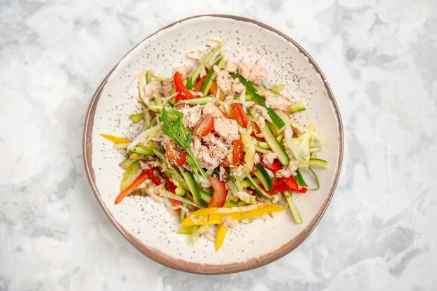 Vue de dessus de la salade de poulet aux légumes sur une surface blanche tachée