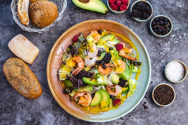 Vue de dessus de la salade de régime sain avec crevettes frites laitue avocat oignon rouge et baies