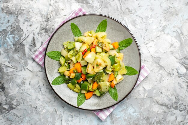 Vue de dessus de la salade de tomates vertes sur une assiette ovale sur fond sombre