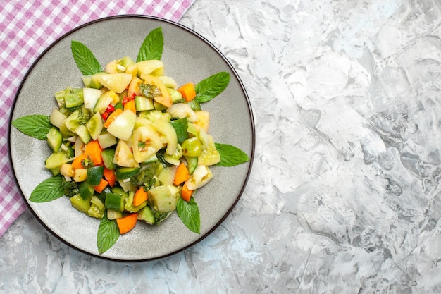 Photo gratuite vue de dessus de la salade de tomates vertes sur une nappe ovale rose sur fond gris avec espace de copie