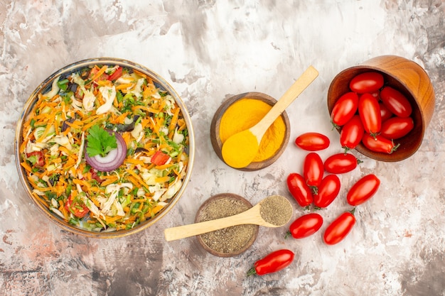 Vue de dessus de la salade végétalienne et des tomates fraîches tombées d'un petit pot d'épices différentes