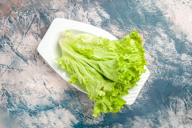 Vue de dessus salade verte fraîche à l'intérieur de la plaque sur fond bleu clair