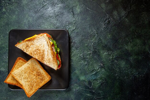 Vue de dessus des sandwichs au jambon avec des toasts à l'intérieur de la plaque sur une surface sombre