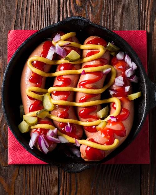 Vue de dessus des saucisses dans une casserole avec des sauces et des oignons