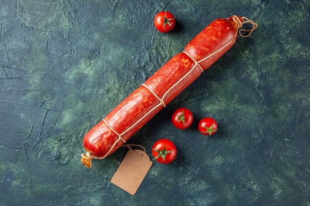 Vue de dessus des saucisses fraîches et savoureuses avec des tomates rouges sur fond sombre pain de viande sandwich repas chignon couleur hamburger d'aliments pour animaux