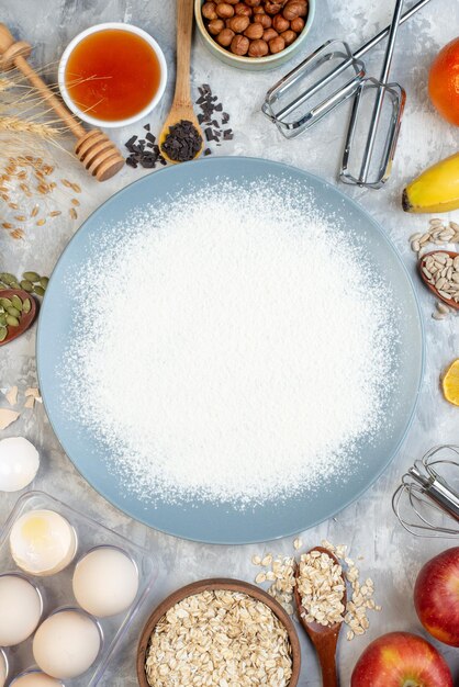 Vue de dessus saupoudré de farine sur une assiette ronde bols de miel et d'avoine oeufs pommes sur table