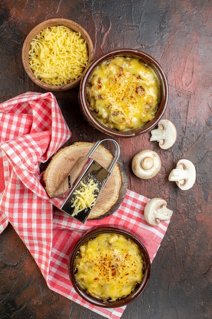 Photo gratuite vue de dessus savoureuse julienne dans un bol poivre noir dans une cuillère en bois râpe à champignons sur planche de bois sur table rouge foncé